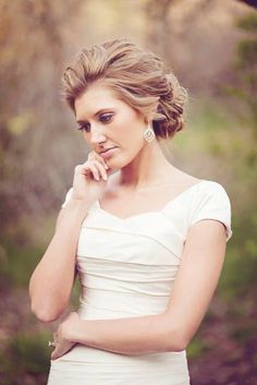 a woman in a white dress is posing for a photo with her hand on her chin