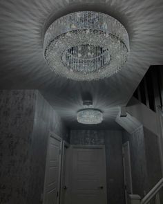 a chandelier hanging from the ceiling in an empty room with stairs leading up to it