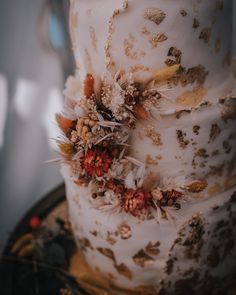 a three tiered wedding cake decorated with flowers and feathers