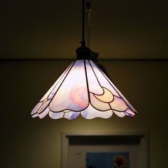 a stained glass light hanging from the ceiling in a room with a door and window