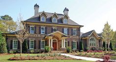 a large brick house with lots of windows and bushes in front of the door area