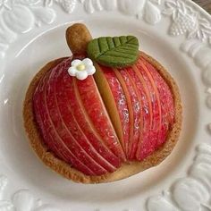 there is a piece of fruit on the plate that looks like an apple with leaves and a flower