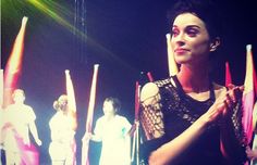 a woman standing in front of flags with her hands on her hips and other people behind her