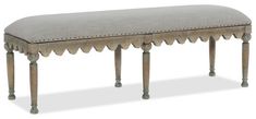 an upholstered bench with scalloped legs and a gray fabric seat cover