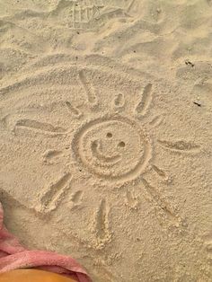 someone's feet in the sand with a smiley face drawn on it