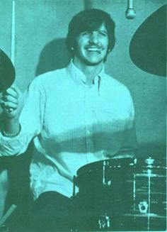 a man sitting in front of a drum set and holding a pair of drumsticks