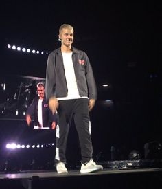 a man standing on top of a stage next to a person wearing white shoes and a black jacket