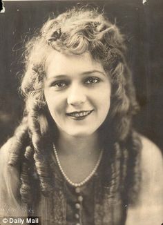 an old black and white photo of a woman with braids on her hair, looking at the camera