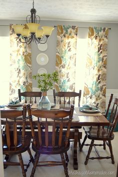 a dining room table with chairs and a vase on top of it in front of the window