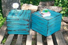 two blue boxes sitting on top of a wooden pallet next to a white flower