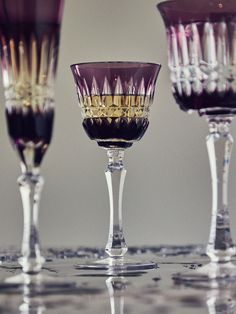 three wine goblets with different colored glassware on the top one is empty