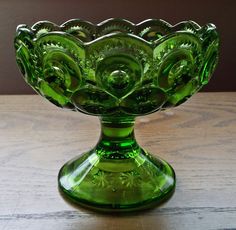 a green glass bowl sitting on top of a wooden table