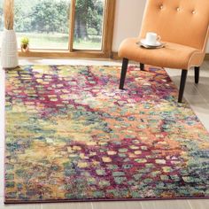 a living room with an orange chair and colorful rug on the floor in front of a window