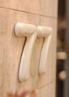 two white handles on a wall near a door