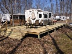 an rv park with several recreational vehicles parked on the deck and in the background are trees