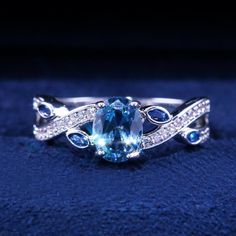 a ring with an oval blue topazte surrounded by diamonds on a blue cloth