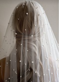 a woman wearing a wedding veil with pearls on the back of her head and hair