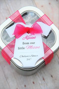 a small metal box with a red bow on it and a card in the middle