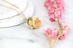 Our unique real white rose bud flowers are preserved in resin, giving you a little piece of nature to carry you through the day! Each piece is unique and may vary in size, as real flowers are used. Our chains are gold plated. Flower Size: approx 2cm x 2cm. Treat earrings with care. Store in a clean, dry place. Do not wear in water. Be careful not to drop or bend them. Due to each item being handmade to order returns or refunds are not available. Colours may vary due to individuals screen calibra Elegant Rose-colored Jewelry With Pressed Flowers, Elegant Rose Jewelry With Pressed Flowers, Elegant Resin Jewelry With Flower Charm, Elegant Resin Birth Flower Jewelry, Elegant Resin Jewelry With Birth Flower Detail, Delicate Gold Resin Jewelry, Elegant Birth Flower Resin Jewelry, Elegant Resin Jewelry For Wedding, Gold Wedding Necklaces With Rose Details