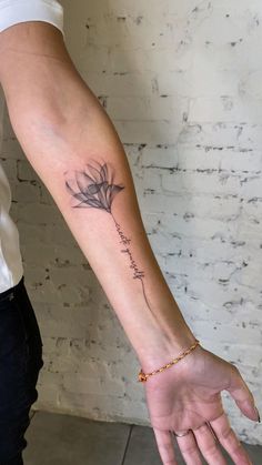 a woman's arm with a small flower tattoo on the left side of her hand