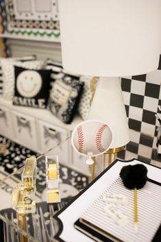 a table with a lamp and baseball on it in a room that has black and white checkered walls