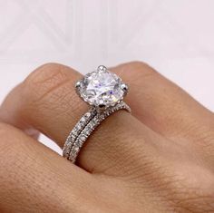 a woman's hand with a diamond ring on top of her finger and an engagement band