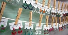 several pairs of earrings are hanging on clothes pegs with name tags attached to them