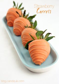 four carrots are arranged on a blue plate with green leaves and the words, strawberry carrots