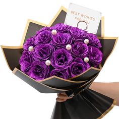 a woman holding a bouquet of purple roses with pearls on the end and a card in her hand