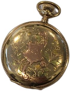 an antique gold pocket watch with floral designs