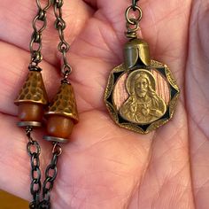 Such a unique and beautiful medal I've never seen. This antique copper medal of Jesus on one side and Mary on the other has guilloché enameling showing bright copper through it and black enameling around the pointed outline. The detail on it is beautiful and the way it has worn over time makes it even more special. It has been hung on a combination of black chain and antique copper chain (I'm having trouble finding this style of old chain) with hammered copper bead caps and antique glass rosary Vintage Black Enamel Medallion Necklace, Vintage Medallion Necklace With Black Enamel, Bronze Medallion Necklace For Memorials, Bronze Medallion Necklace For Memorial, Memorial Medallion Necklace With Antique Finish, Antique Copper Medallion Necklace, Memorial Bronze Engraved Necklaces, Memorial Bronze Engraved Necklace, Vintage Necklace With Black Enamel For Gift