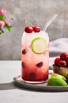 a drink with cherries and lime on a plate