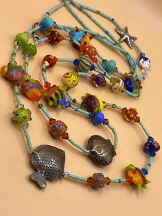 "Handmade Vintage Lampwork Glass Sterling Silver \" Under The Sea \" Artisan One Of A Kind Necklace . Each bead has attention to detail with many sterling touches . This beautiful ocean themed necklace has 3 large sterling beads ( Fish, Shell, & Starfish) the lobster claw clasp is 925 Silver . Please remember all items are vintage & estate found, therefore do not expect perfection as they may show some wear or imperfections only adding to the character & authenticity. All items are identified and described as accurately as possible with all information on hand at the time the listing was made. no expertise is claimed on any items for sale. Thank You" Artisan Beaded Necklaces With Sterling Silver Clasp, Artisan Beaded Necklace With Sterling Silver Clasp, Handmade Multi-strand Glass Jewelry, Ocean-inspired Colorful Beads For Jewelry Making, Artistic Handmade Beach Jewelry, Bohemian Glass Jewelry With Single Strand, Bohemian Glass Single Strand Jewelry, Beach Jewelry With Large Glass Beads, Whimsical Handmade Glass Jewelry