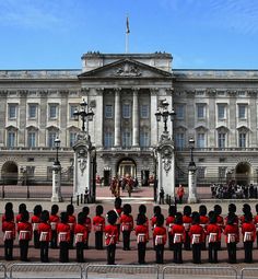 the guards are standing in front of the building with people dressed in red and black