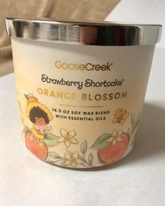 an orange blossom candle is sitting on a white counter top, with the label goose creek strawberry shortcakes