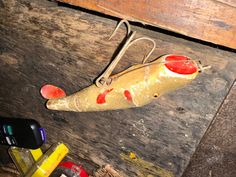 an old fishing lure sitting on top of a wooden table next to some other items