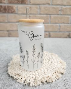 a glass jar sitting on top of a white rug next to a brick wall with the words grow in grace written on it