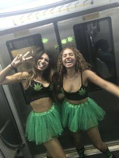 two women in green skirts standing on a subway train