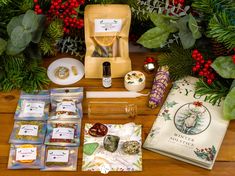 various items are displayed on a table with evergreens and other holiday decorations in the background