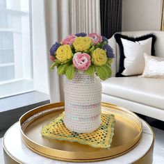 a crocheted vase with flowers on a tray