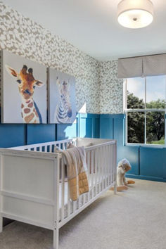 a baby's room with blue and white wallpaper, giraffes on the wall