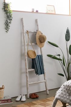 a ladder leaning up against a wall with hats on it and shoes hanging off the floor