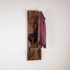 the coat rack is made out of wooden slats and holds an umbrella, shoes, and scarf