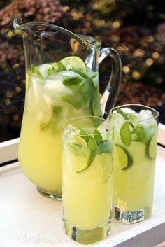 two pitchers and glasses filled with lemonade on a table