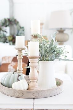 a white tray with candles on top of it and some flowers in the centerpiece