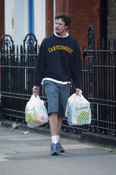 a man walking down the street carrying two bags