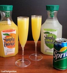 some drinks are sitting on a table next to two bottles and an empty glass with orange juice in it