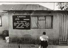 a person sitting on the ground in front of a building with a sign that reads castle