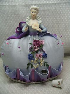 a doll sitting on top of a decorative pillow