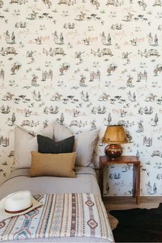 a bedroom with a bed, nightstand and wallpaper in the background that has horses on it